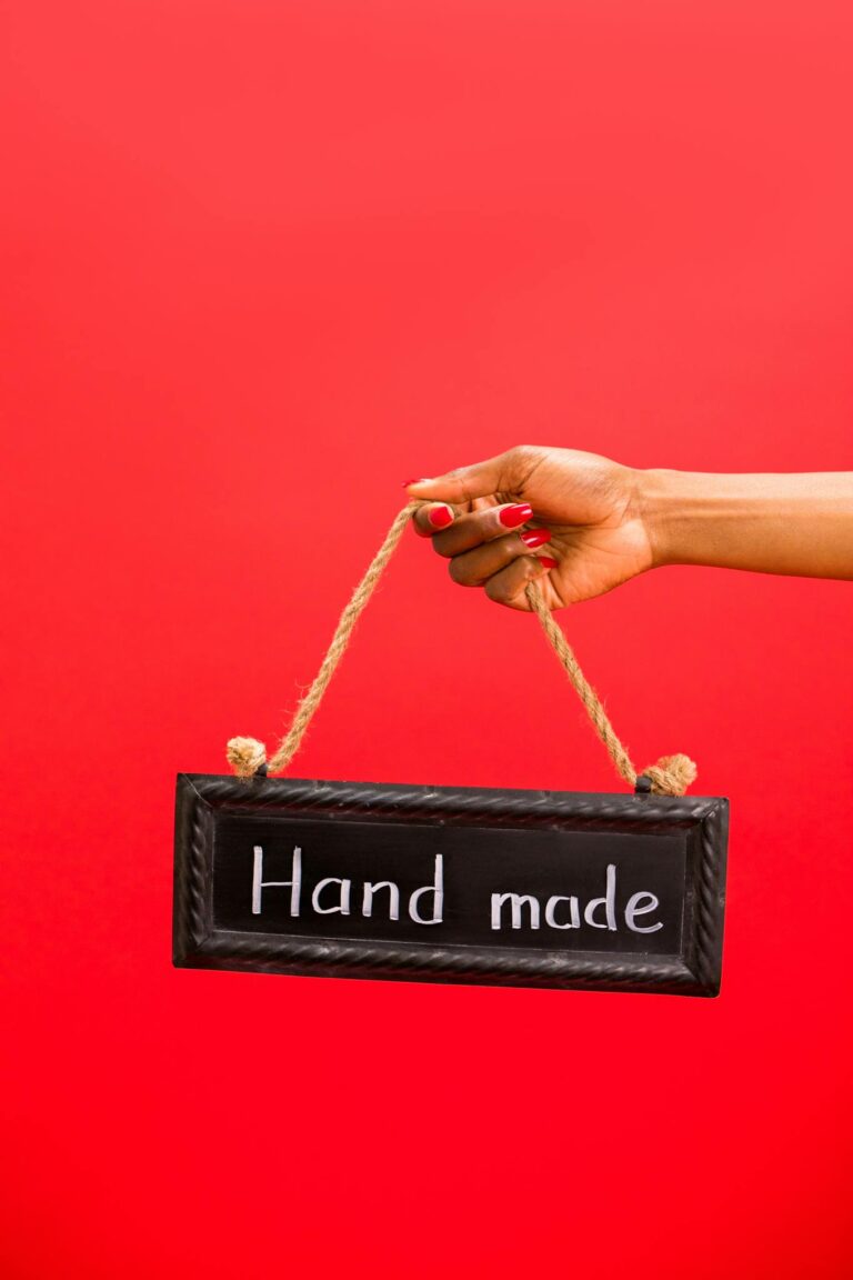 A hand holding a handmade sign with rope against a vibrant red backdrop.