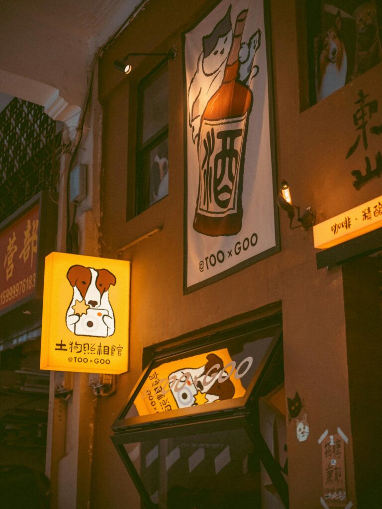 Brightly lit neon signs featuring cute animal designs in an Asian night market.